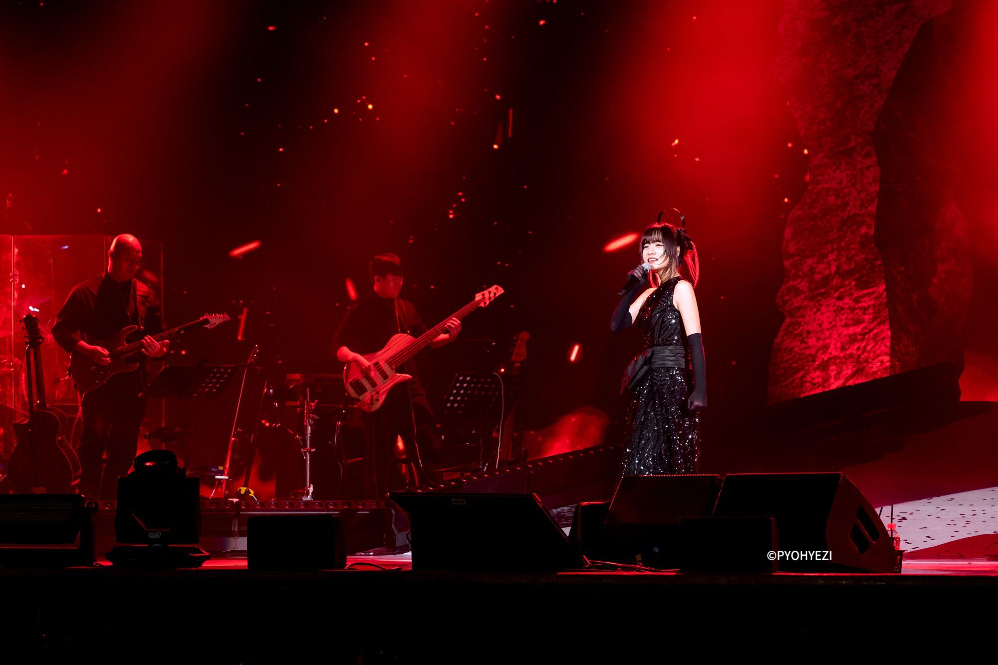 ライブパフォーマンスの写真：ギター、ベース奏者と歌う シム･ギュソン。単独コンサート「Monster 」より。